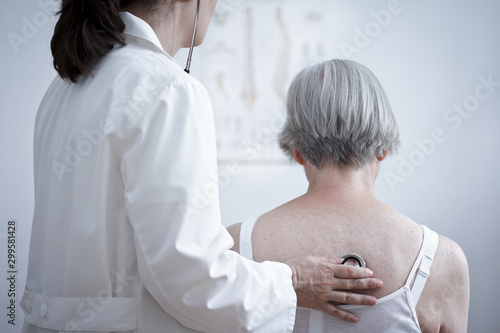 Health care concept: female doctor auscultating the lungs of a senior patient with a stethoscope.