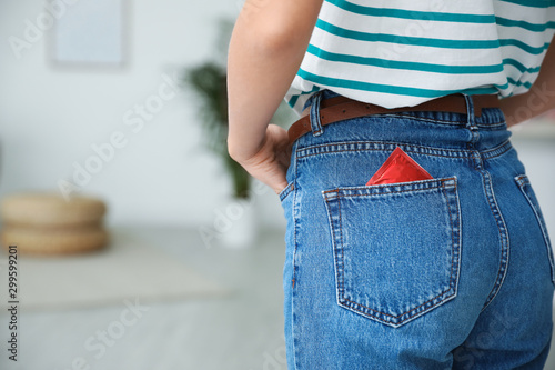 Woman with condom in pocket of her jeans indoors, closeup. Safe sex concept