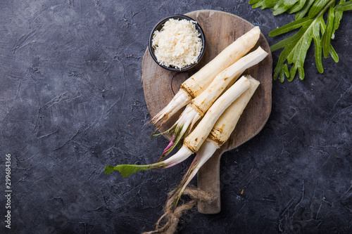 Fresh orgaanic horseradish or Horse-radish root on wooden cutting board. top view