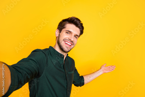 Close up photo of positive cheerful guy hold hand take selfie invite his blogging followers to perfect rest relax through video call wear casual style outfit isolated over yellow color background