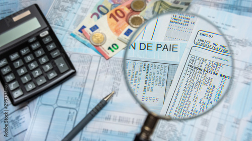 Bulletin de paie français à la loupe, avec argent liquide en euros, calculette et stylo