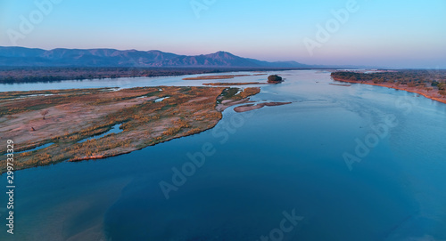 Aerial, east view of Zambezi river during sunset. View on african wilderness, mountains and huge river Zambezi from above. Border river. UNESCO Heritage Site, Mana Pools National Park, Zimbabwe.