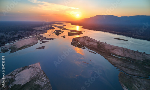 Aerial, west view of Zambezi river, mountains and african wilderness. Colorful sunset reflecting on huge Zambezi river, view from above. UNESCO heritage site, Mana Pools national park, Zimbabwe.