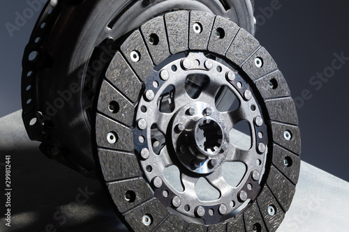 Close-up picture of a part of car, black clutch disk isolated on black background with light