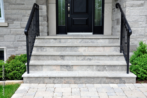 Flagstone applied to the original concrete veranda, natural stone steps, and a tumbled paver landing all provide a beautiful, fresh landscape update to this mid century modern bungalow.