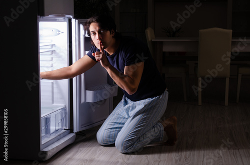 Man breaking diet at night near fridge