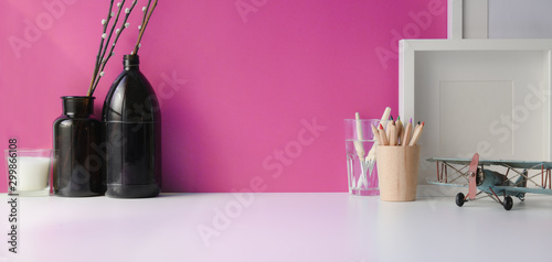 Professional artist workspace with painting tools and decorations with copy space on white table and pink wall
