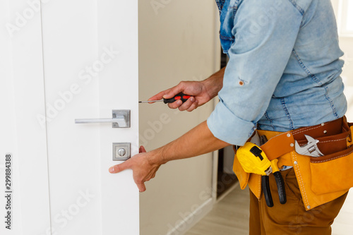 young repairman checking new door lock