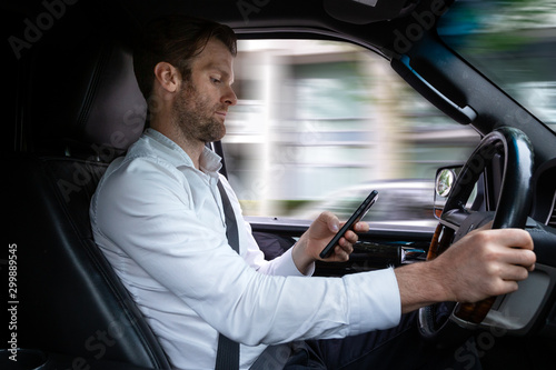 A middle aged caucasian man distracted driving while using a mobile device.