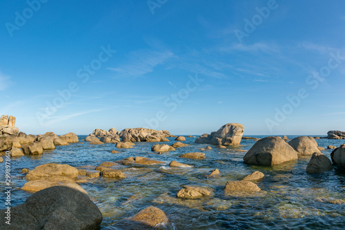 calm ocean and coast with large rocks and granite boulders in morning light