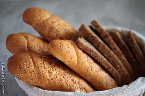 Fresh bread baguette with sesame seeds and slices of rye bread are in the breadbox on the table. Bakery. Flat lay. Close-up, minimalism.