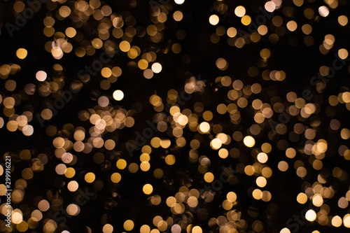 Blurry golden and white fairy string lights in dark night creating beautiful bokeh effect with glowing circles or shiny dots, abstract image for Christmas or holiday card, banner or background