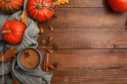Grey cup of coffee with milk and spices, plaid, yellow oak leaves, acorns, orange pumpkins on dark brown wooden table. Autumn drink concept. Fall, pumpkin spicy latte, thanksgiving, top, copy space
