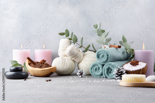 Beautiful spa and relax winter concept. Coffee with cinnamon scrub, cotton pouches with herbs for massage, sea stones, eucalyptus and other Spa accessories on grey table.