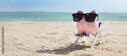 Pink Piggybank On Deck Chair Over The Sandy Beach