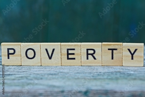 the word poverty from wooden letters on a gray table on a green background