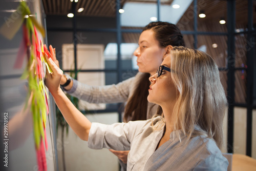 Teamwork, project management, agile methodology. Two young business women in the office