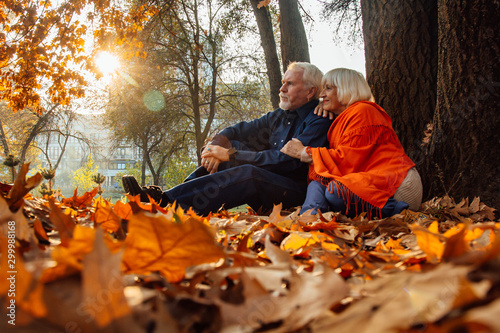 Close up portrait of a happy old woman and man in a park in autumn foliage.