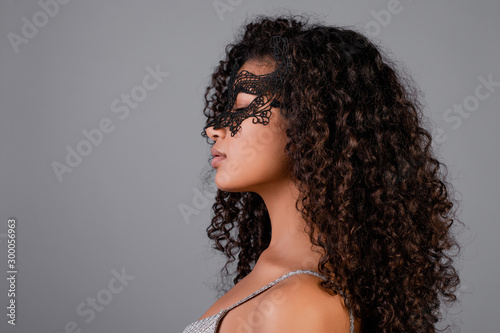 beautiful black woman wearing elegant masquerade mask isolated over grey