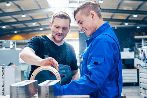 Master discussing a workpiece with his apprentice or trainee