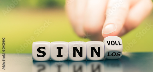 Hand dreht einen Würfel und ändert das Wort "sinnlos" in "sinnvoll".