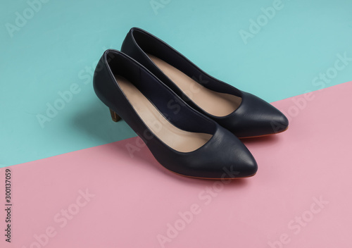 Classic leather high heel shoes on a pastel pink-blue background. Minimalistic fashion still life. Studio shot