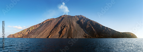 The stromboli vulcano erupting on the "Sciara del Fuoco" north west side, day shot, blue sky background, panoramic shot, eolians islands, sicily, italy
