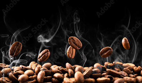 Ziarna kawy spadają w dym na czarnym tle. Palenie kawy