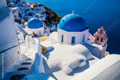 Traditional white architecture and greek orthodox churches with blue domes over the Caldera in Aegean