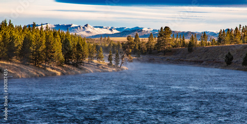 Madison river in Yellowstone nation park with snow top mountains and forest