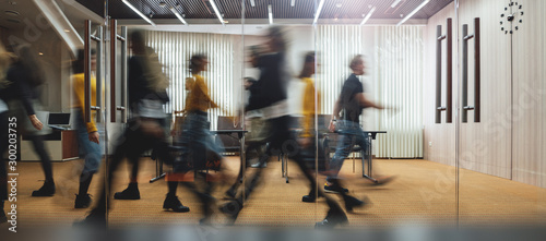 Businesspeople walking at modern office. Group of business employees at coworking center. Motion blur. Concept work process. Wide image