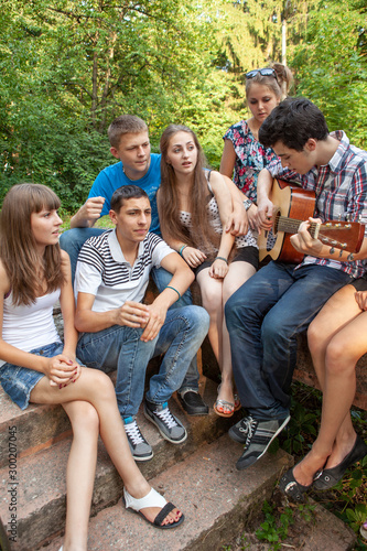 Cheerful teenagers playing guitar and singing