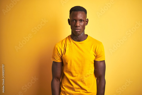 Young african american man wearing casual t-shirt standing over isolated yellow background skeptic and nervous, frowning upset because of problem. Negative person.