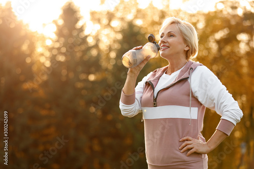 Sporty mature woman with bottle of water outdoors