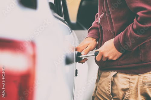 Car theft thief stealing vehicle. Street crime man breaking in automobile to steal.