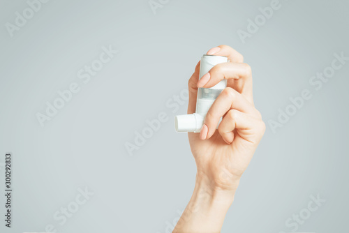 Female hand holding a medical asthma inhaler.