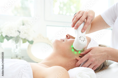 Ultrasonic facial massage, light phototherapy. Ultrasonic facial massage using light therapy. Professional treatment in a cosmetics clinic.