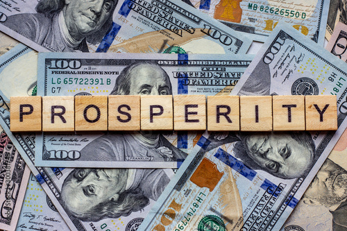 The word prosperity on dollar usa background. Welfare, sufficiency and wealth concept