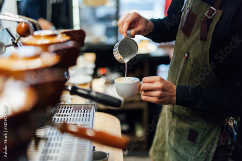 Barista making coffee in coffee shop, hands holding cup of coffee.