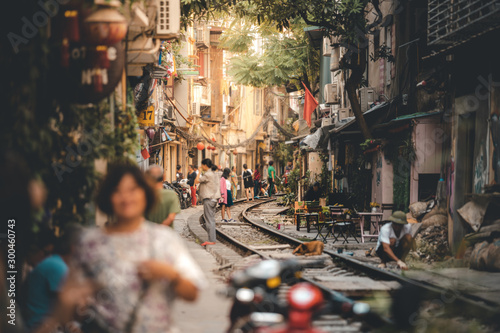 Tourists walk down and drink coffee along the tracks of the famous Train Street in Hanoi, Capital of Vietnam