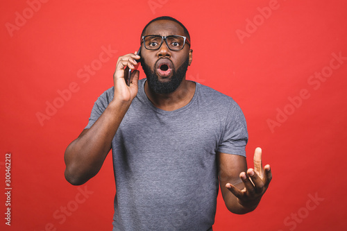 Young handsome man talking on the phone cover mouth with hand shocked with shame for mistake, expression of fear, scared in silence, secret concept. Isolated over red background.