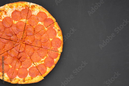 Tasty Pepperoni pizza over black surface, top view. Overhead, from above, flat lay. Space for text.