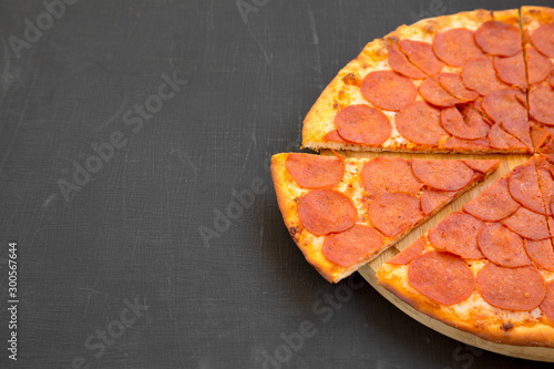 Tasty Pepperoni pizza over black background, low angle view. Copy space.