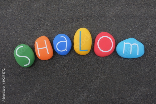 Shalom, Jewish greeting or saying goodbye concept composed with multi colored carved stone letters over black volcanic sand