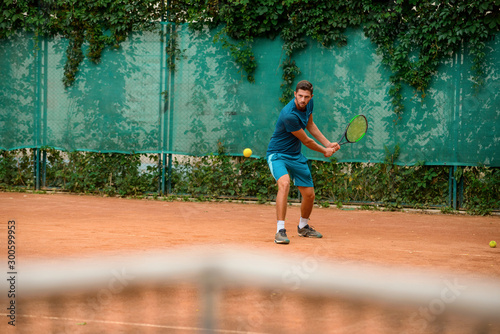 Skilled male tennis player at outdoor court