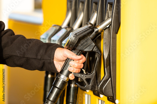 Hand with fuel nozzle at a gas station