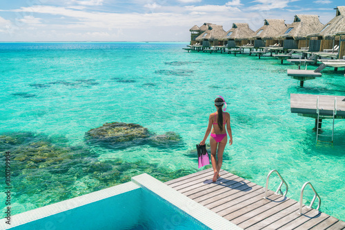 Luxury overwater bungalows Tahiti resort woman going snorkeling from private hotel room on Bora Bora island, French Polynesia. Travel vacation recreational activity watersport fun leisure.