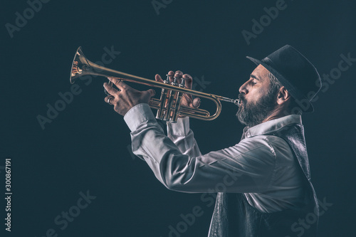 profile view of a jazz trumpet player with beard and hat.