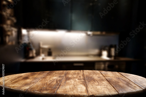 Wooden table background of free space for your decoration and blurred background of kitchen. Copy space.Dark mood interior. Kitchen furniture. 