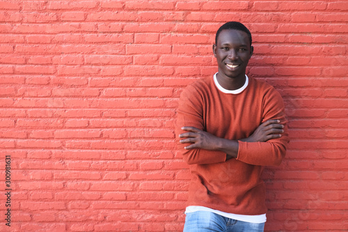 African Young Man Smiling With Red Wall In Background